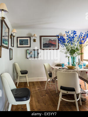 Painted chairs with leather seats by Christopher Howe in dining room with  artworks of Vesuvius Stock Photo