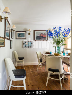 Painted chairs with leather seats by christopher Howe in dining room with gouache artsworks of Vesuvius Stock Photo