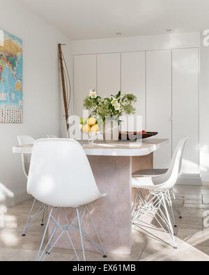 White plastic Eames chairs around custom made table of lime and waxed oak Stock Photo
