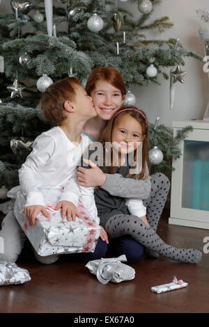 Christmas Eve, happy siblings with Christmas presents under the Christmas tree, Bavaria, Germany Stock Photo