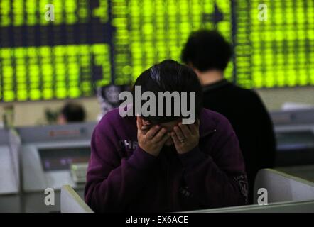 Nantong, China. 08th July, 2015. An investor watches the eclectic monitor at a stock exchange in Nantong, Jiangsu province, China on 8th July 2015. The CSI300 index of the largest listed companies in Shanghai and Shenzhen close down 6.8 percent, while the Shanghai Composite Index dropped 5.9 percent. Credit:  Panda Eye/Alamy Live News Stock Photo