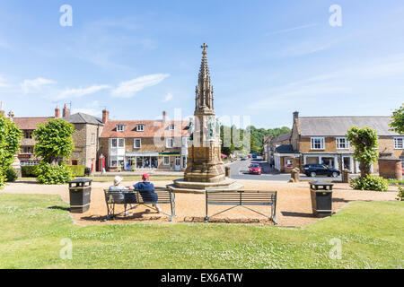 Couple relaxing on a metal bench by the Digby Memorial in front of Sherborne Abbey, Sherborne, Dorset on a sunny summer day Stock Photo