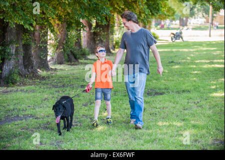 Father and son walking black labrador dog together holding hands Stock Photo