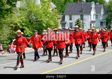 A group of Royal Canadian Mounted Police RCMP officers in red ceremonial uniform marching in a parade lead by a female officer