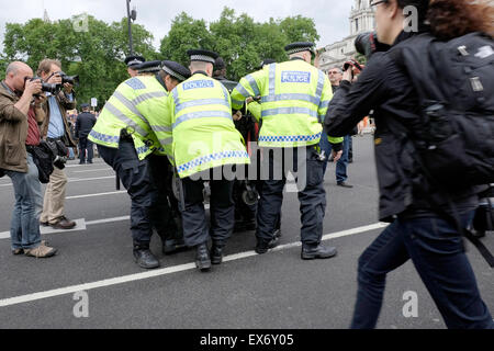 Police officers try to lift a wheelchair user at a protest against welfare cuts Stock Photo