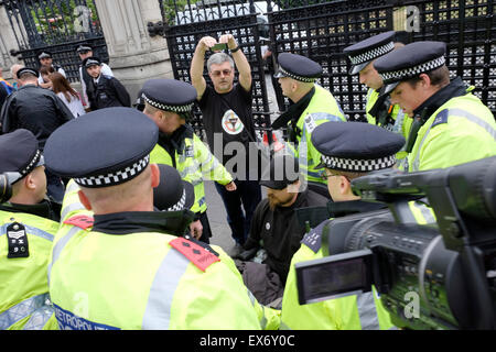 Police officers surround a wheelchair user outside the houses of Parliament Stock Photo