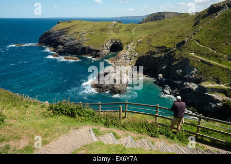 A man looking down on the Cornish coastline from Tintagel Castle, Cornwall, England, UK Stock Photo