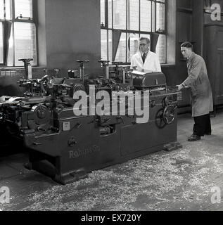1950s, historical, woodworking, two engineers in overalls working with a large wood-working lathe made by Thomas Robinson and Son of Rochdale, specialist makers of wood cutting machinery, a company established in 1838. Stock Photo