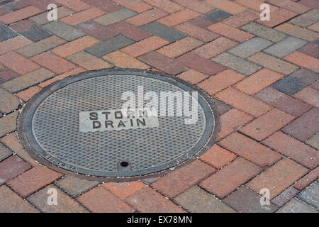 Storm Drain Cover on a Brick Road Stock Photo