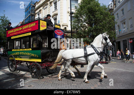 Summertime in London, England, UK. Horse-drawn omnibus giving tourists a different perspective on the tour bus. The tours which are operated on a fully restored eighteen-seater horse-drawn omnibus are the perfect way to enjoy the vibrancy of the West End. With the steady sound of horses pulling the carriage. Stock Photo