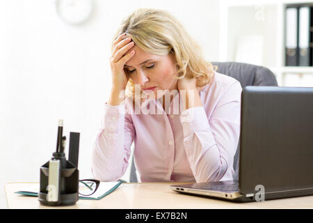 Tired middle-aged businesswoman in her office looking down Stock Photo