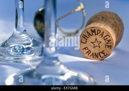 Champagne cork on white tablecloth with glasses wire retaining frame and cap in fine dining situation Stock Photo
