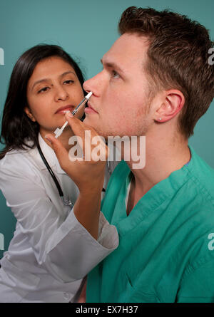 Healthcare worker administering an intranasal influenza vaccine in a patient's nostril. Stock Photo