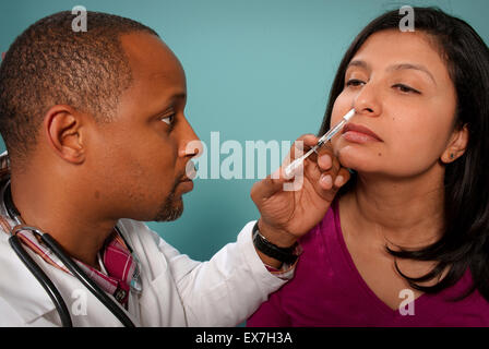 Healthcare worker administering an intranasal influenza vaccine in a patient's nostril. Stock Photo