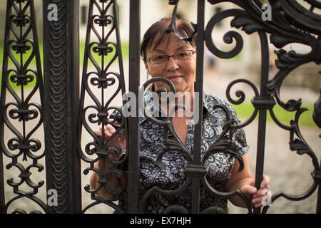 Mature woman standing behind a metal fence in the Park. Stock Photo