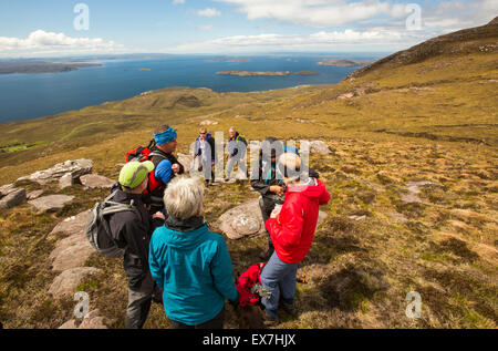A walking group on Ben Mor Coigach, looking towards the Summer Isles, near Ullapool, Scotland, UK. Stock Photo