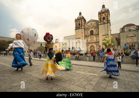 Women in costume and large figures dancing in front of Santo Domingo Church at a traditional festival in Oaxaca Mexico Stock Photo