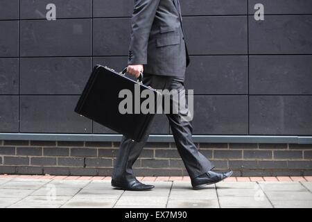 A business man carries a briefcase on the way to work at an office. Stock Photo