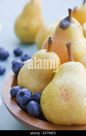 Juicy pears in bowl with fresh blueberry, selective focus Stock Photo