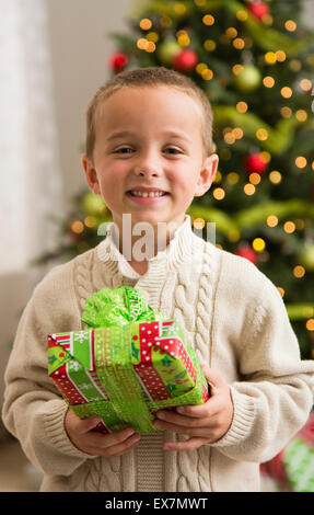 Boy (6-7) holding Christmas present Stock Photo