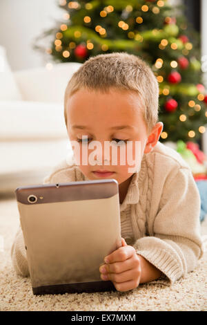 Boy (6-7) using digital tablet lying on carpet Stock Photo