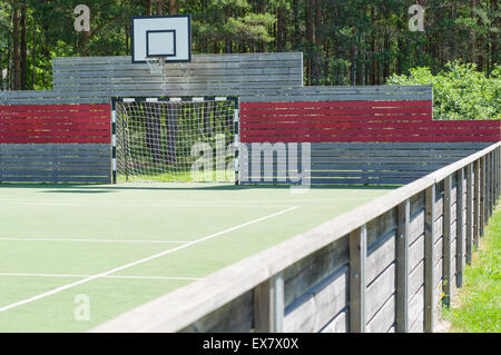 Soccer goal and basketball hoop on universal outdoor playground with synthetic field and wooden fence Stock Photo