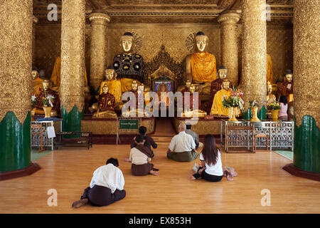 People meditating in front of Buddha statues, Shwedagon Pagoda, Yangon, Myanmar Stock Photo