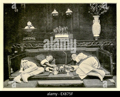 Wealthy Opium smokers in an upper-class Opium den in Shanghai city, China circa 1908. In center foreground teapot and tobacco pipe. Photograph of original photograph by Mencarini published in 1908. Stock Photo