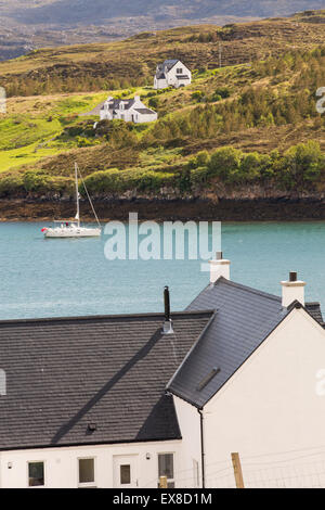 Modern houses in Tarbert on the Isle of Harris, Outer Hebrides, Scotland, UK, with a sailing boat coming ito port. Stock Photo