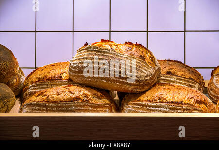 Fresh hot bread on the wooden shelf with white ceramic tiles wall on background Stock Photo