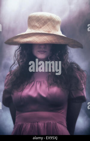 a woman is hiding behind her sunhat Stock Photo