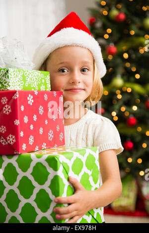Girl (6-7) holding stack of Christmas presents Stock Photo