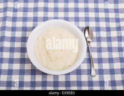 A bowl of white corn grits on a blue plaid placemat Stock Photo