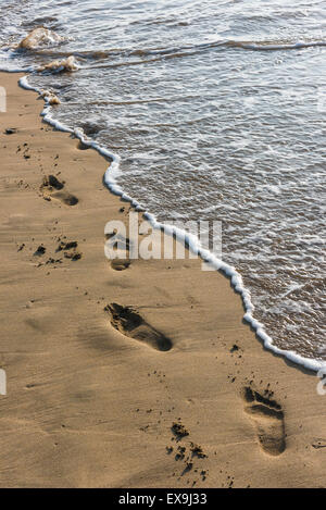 Footsteps in the sand along the shoreline on Crantock Beach in Newquay, Cornwall. Stock Photo