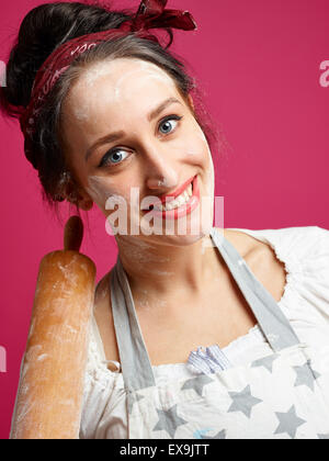 Close up, funny housewife and kitchen utensil, pink background Stock Photo