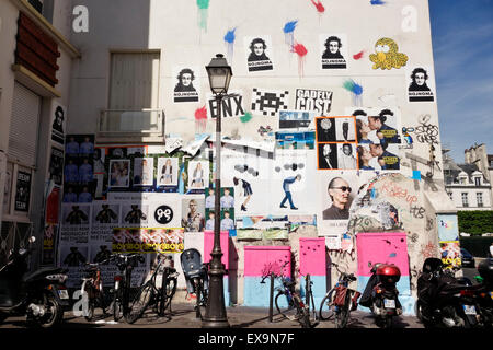 Street art mixed with promotional fashion posters on wall in Paris, France. Stock Photo