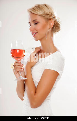 Portrait of happy smiling young attractive blonde woman with glass of red rose wine, in white dress isolated on white background Stock Photo