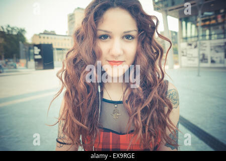 young beautiful hipster woman with red curly hair listening music in the city Stock Photo
