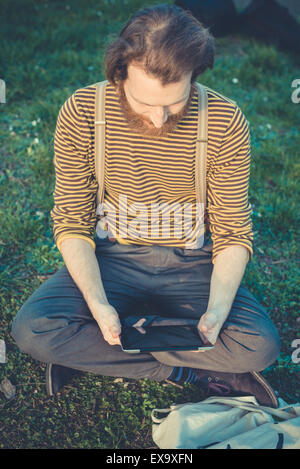 young bearded stylish handsome hipster man using tablet outdoors Stock Photo