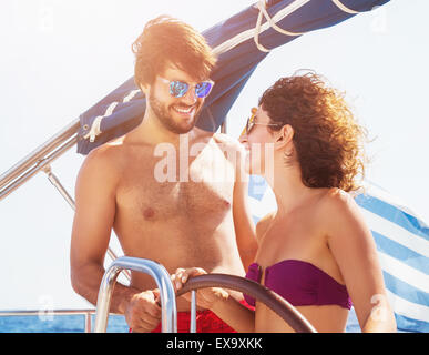 Cheerful couple driving sailboat, handsome guy and cute girl laughing and looking with love on each other Stock Photo