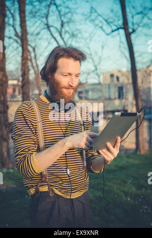 young bearded stylish handsome hipster man using tablet outdoors Stock Photo