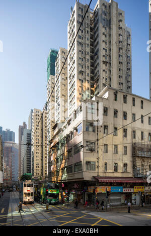China, Hong Kong, Tramway streetcars driving along busy street  beneath apartment towers on winter day Stock Photo