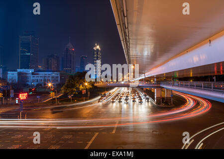 China, Shanghai, Blurred image of car and bus traffic of Yan’an Road beneath concrete overpass on autumn evening Stock Photo