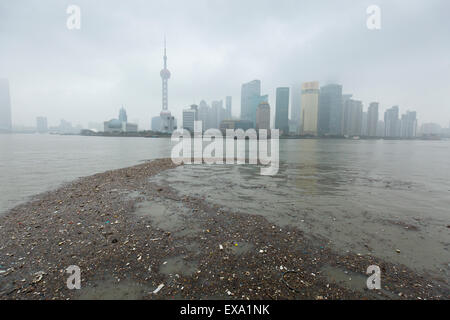 China, Shanghai, Vast pool of trash floats past skyline of Pudong District beneath low clouds along Huangpu River on winter morn Stock Photo