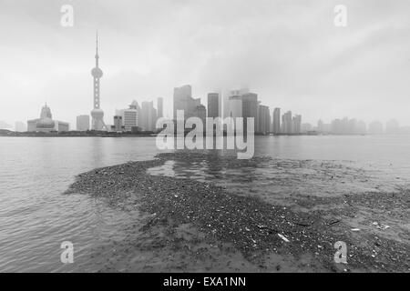 China, Shanghai, Vast pool of trash floats past skyline of Pudong District beneath low clouds along Huangpu River on winter morn Stock Photo