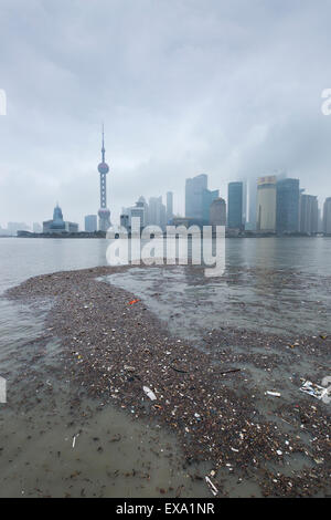 China, Shanghai, Vast pool of trash floats past skyline of Pudong District beneath low clouds along Huangpu River on winter morn Stock Photo