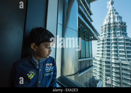 Asia, Malaysia, Kuala Lumpur, Young boy peers through window on 86th Floor Observation Deck of top of Petronas Towers Stock Photo