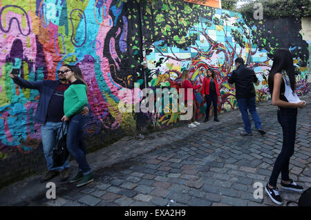 Sao Paulo, Brazil. 9th July, 2015. Residents pose in front of a graffiti at the Batman's Alley, in Vila Madalena of Sao Paulo, Brazil, July 9, 2015. Walls in Batman's Alley are painted with graffiti of different urban artists. The works are constantly changed, according to local press. © Rahel Patrasso/Xinhua/Alamy Live News Stock Photo