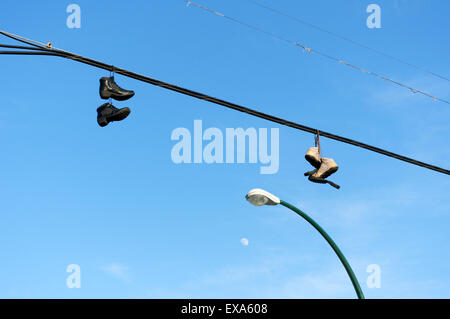 Boots and running shoes hanging from an overhead wire, Vancouver, Canada Stock Photo
