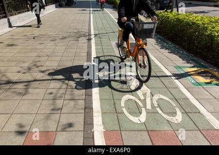 Asia, Taiwan, Taipei,  Shadow of rider peddling bicycle near Dongmen Market along Xin Yi Road on sunny winter morning Stock Photo